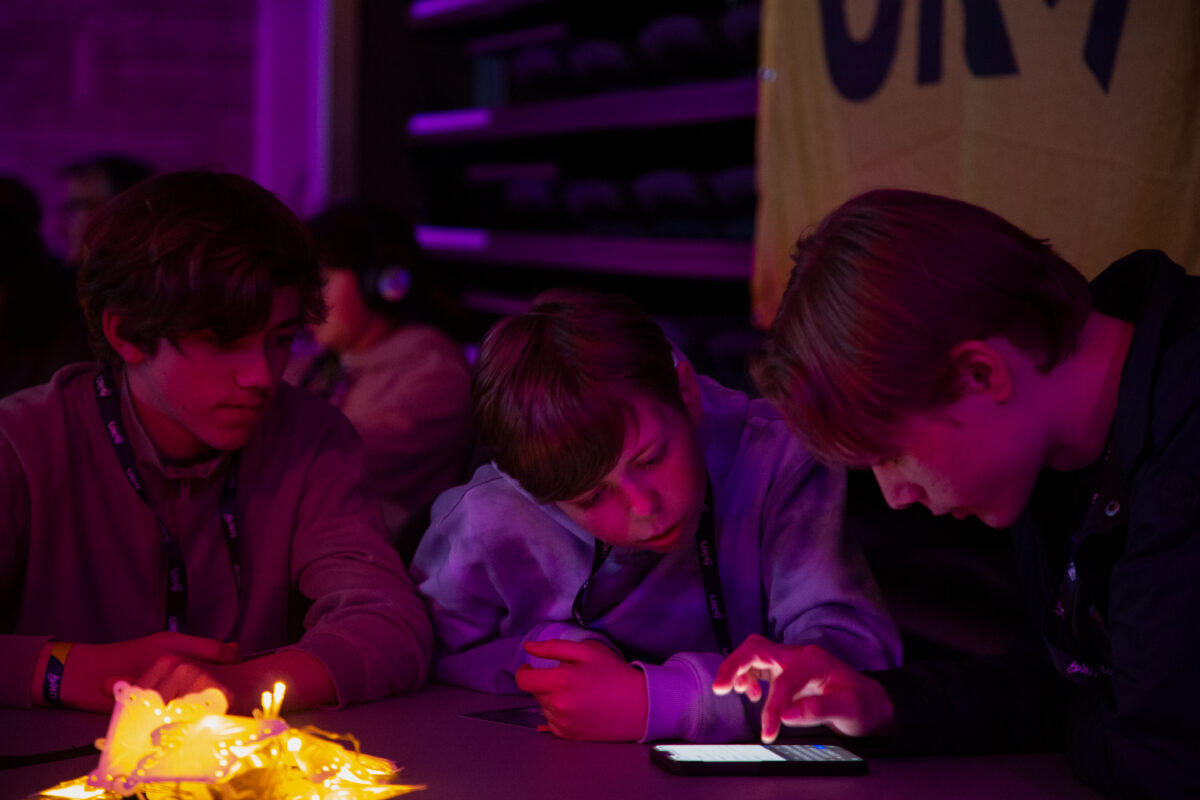 Tre gutter ser pÄ telefonen. Foto