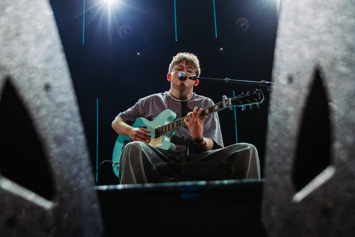 Artist som synger og spiller gitar på scenen
